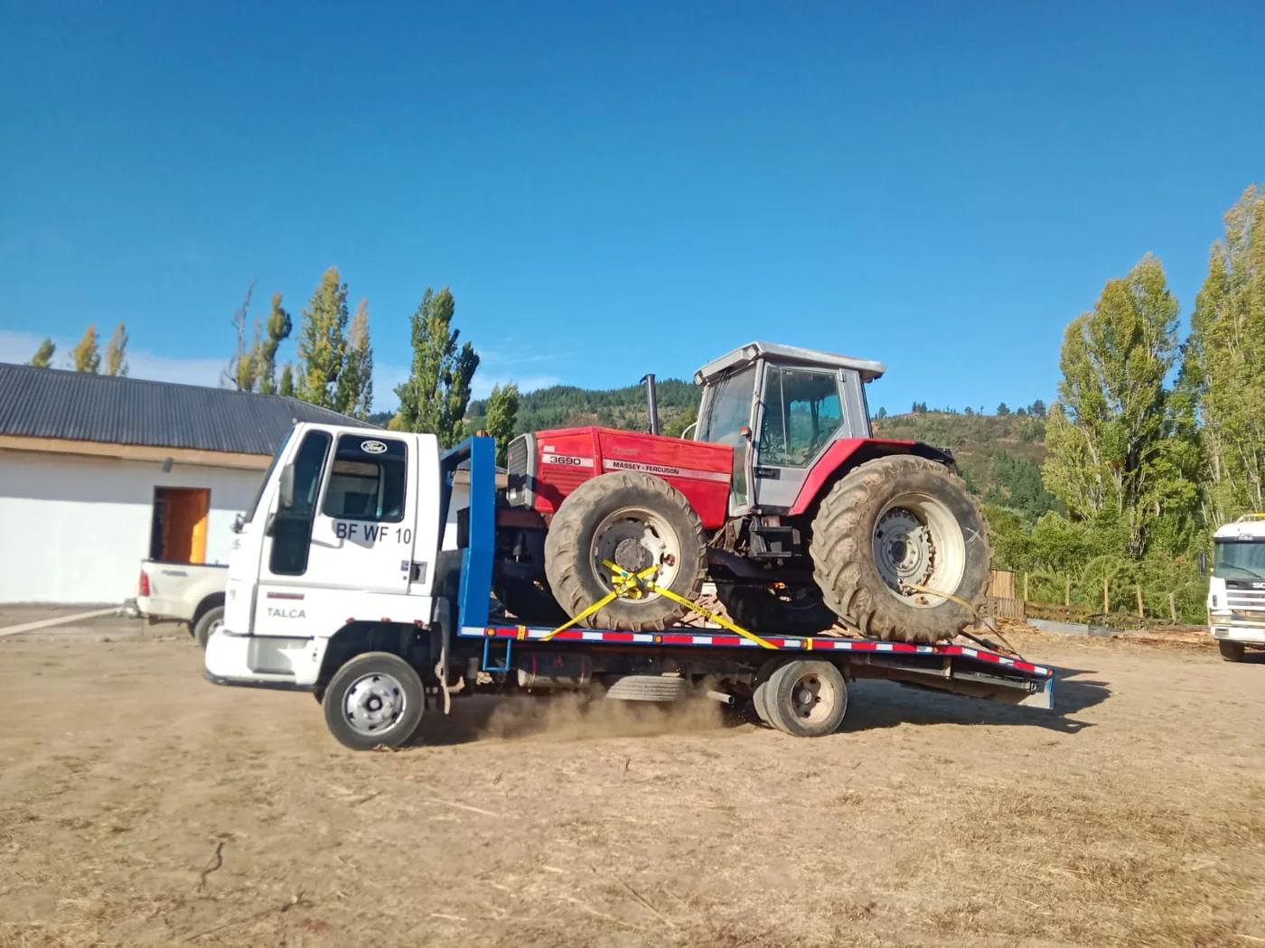 Grúa trasladando tractor rojo
